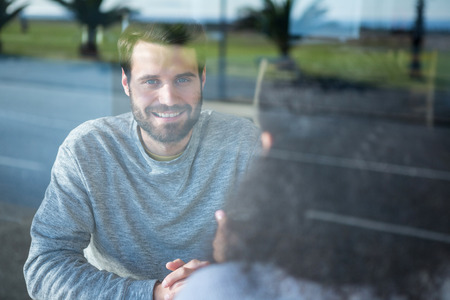 Smiling man talking to a woman in coffee shopの写真素材