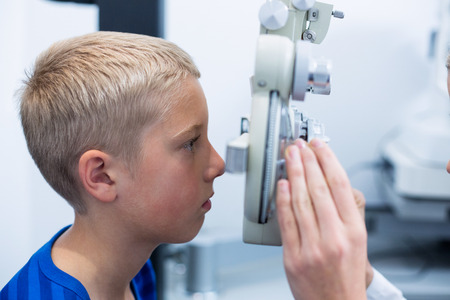 Young patient under going eye test through phoropter in ophthalmology clinicの写真素材