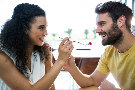 Romantic couple feeding each other dessert in coffee shopの写真素材