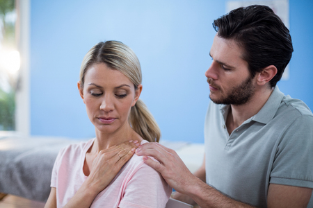 Physiotherapist massaging shoulder of a female patient in the clinicの写真素材