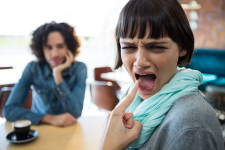 Woman showing burned tongue in cafeteriaの写真素材