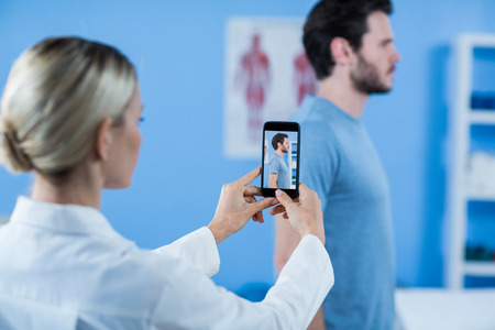 Physiotherapist clicking photo of a male patient in the clinicの写真素材