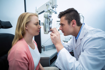Optometrist examining female patient on phoropter in ophthalmology clinic