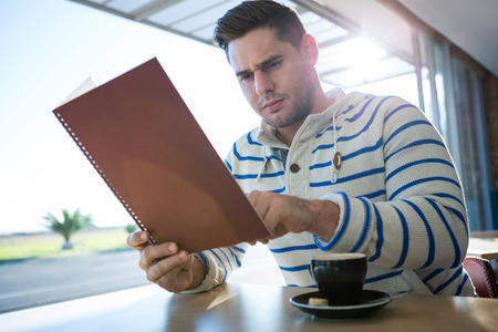 Man checking out the menu in coffee shopの写真素材