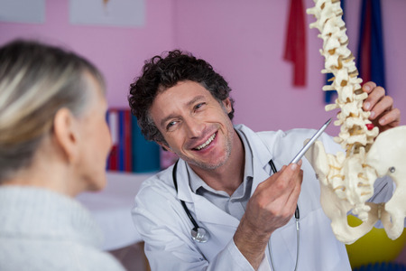 Physiotherapist explaining the spine model to patient in clinic