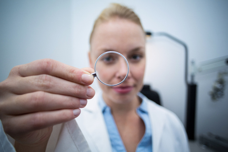 Close-up of female optometrist looking through magnifying glass in ophthalmology clinicの写真素材