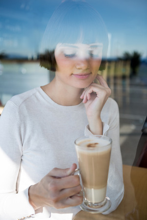 Thoughtful woman having milkshake in cafeteriaの写真素材