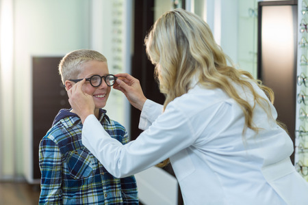 Female optometrist prescribing spectacles to young patient in optical storeの写真素材