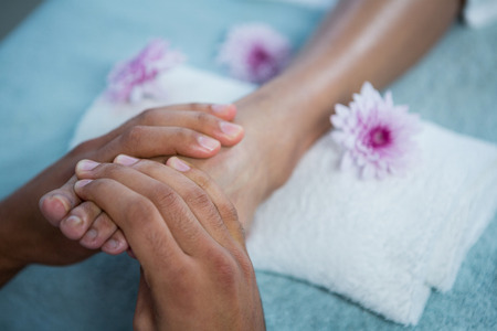 Physiotherapist giving foot massage to a woman in clinicの写真素材