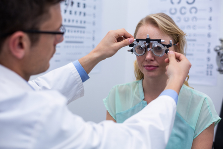 Optometrist examining female patient with phoropter Optometrist examining female patient with phoropterの写真素材
