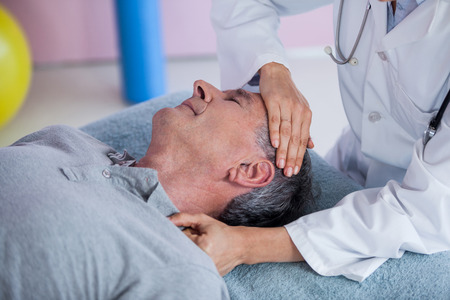Senior man receiving neck massage from physiotherapist in clinicの写真素材