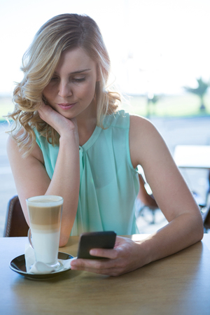 Beautiful woman using her mobile phone in the coffee shopの写真素材