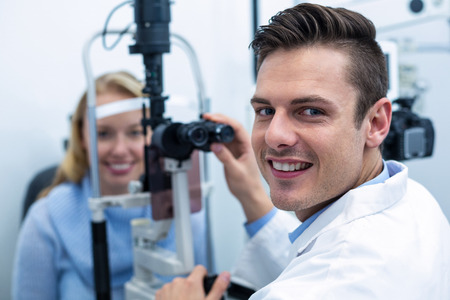 Portrait of optometrist examining female patient on slit lamp in ophthalmology clinic