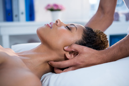 Woman receiving neck massage from physiotherapist in clinicの写真素材