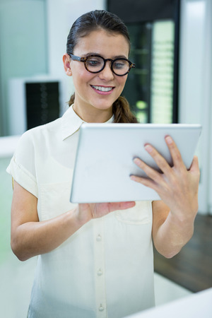 Female customer using digital tablet in optical storeの写真素材