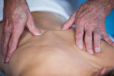 Woman receiving back massage from physiotherapist in clinicの写真素材