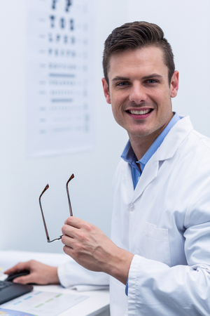 Portrait of handsome optometrist working in ophthalmology clinicの写真素材
