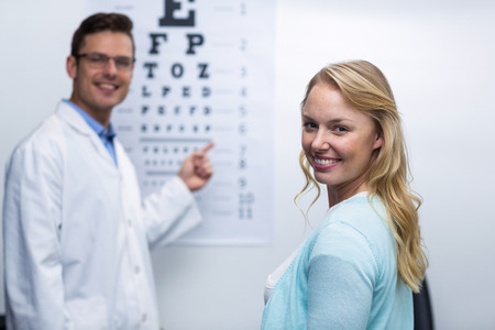 Optometrist taking eye test of female patient in ophthalmology clinicの写真素材