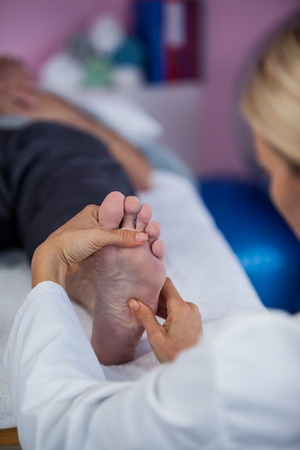 Physiotherapist giving foot massage to a patient in clinicの写真素材