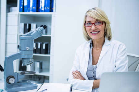 Portrait of smiling optometrist sitting with arms crossed in ophthalmology clinicの写真素材