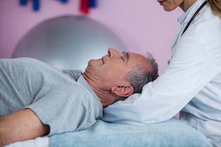Senior man receiving neck massage from physiotherapist in clinic