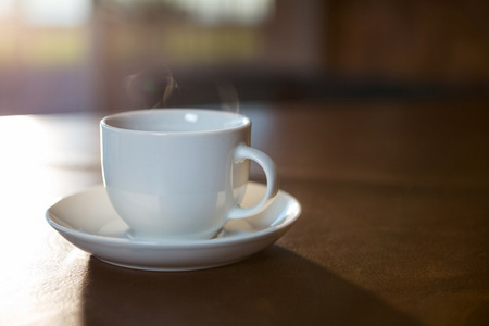 Close-up of coffee cup with saucer on a table in coffee shopの写真素材