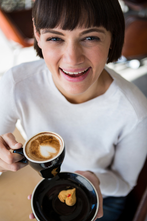 Portrait of smiling woman having cup of coffee in cafeteriaの写真素材