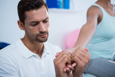 Physiotherapist massaging hand of a female patient in the clinicの写真素材