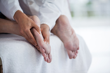 Senior man receiving foot massage from physiotherapist in clinicの写真素材
