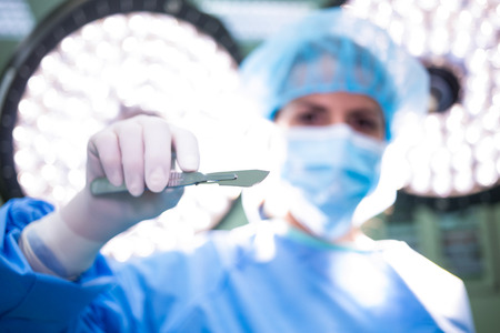 Female surgeon holding medical equipment in operation room at hospital