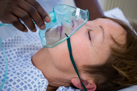 Nurse placing an oxygen mask on the face of a patient in hospital