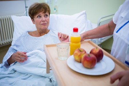 Nurse serving a breakfast to patient in hospitalの写真素材