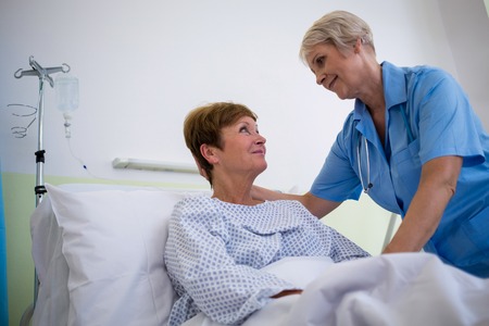 Nurse talking to a senior patient in hospital roomの写真素材