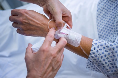 Nurse attaching iv drip on patient s hand in hospitalの写真素材