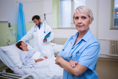 Portrait of nurse standing with arms crossed in hospital roomの写真素材