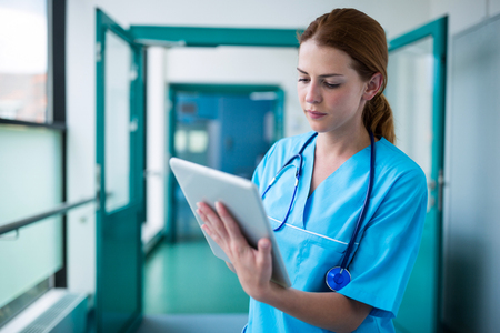 Surgeon using digital tablet in corridor at hospitalの写真素材
