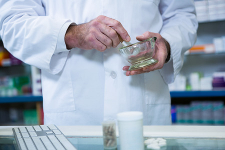 Pharmacist grinding medicine with mortar and pestle at pharmacyの写真素材