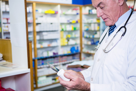 Pharmacist holding digital tablet while checking medicine in pharmacyの写真素材