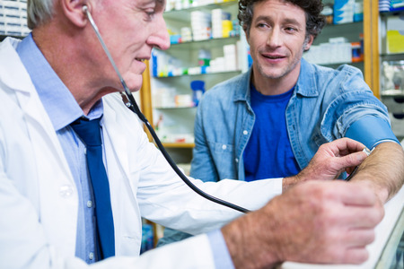 Pharmacist checking blood pressure of customer in pharmacy