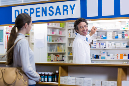 Pharmacist showing the medicine box to customer in pharmacyの写真素材
