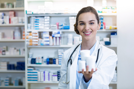 Portrait of pharmacist showing medicine container in pharmacyの写真素材