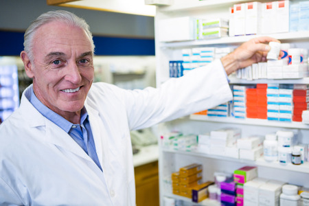 Portrait of pharmacist checking a bottle of drug in pharmacyの写真素材