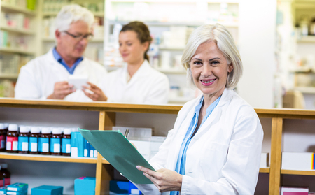 Portrait of pharmacist writing on clipboard in pharmacyの写真素材