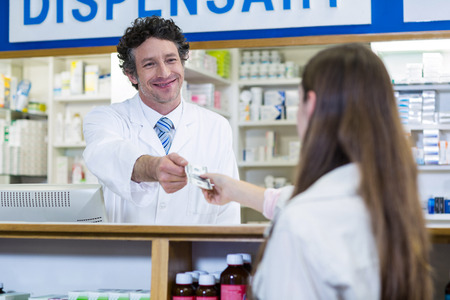 Pharmacist receiving payment from customer in pharmacyの写真素材