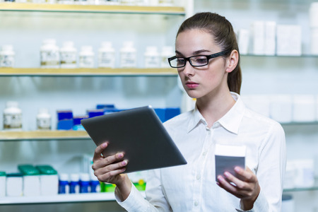 Pharmacist using digital tablet while checking medicine in pharmacyの写真素材