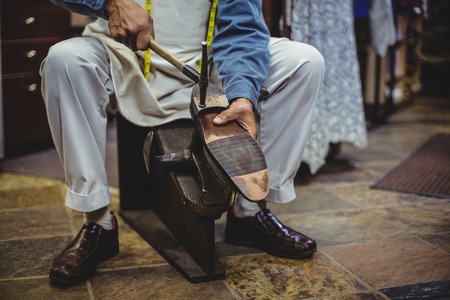 Shoemaker hammering on a shoe in workshopの写真素材
