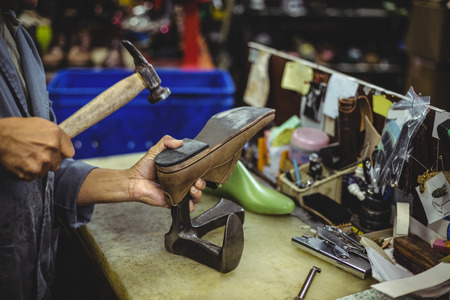Shoemaker hammering on a shoe in workshopの写真素材