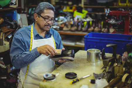 Shoemaker polishing a shoe in workshopの写真素材
