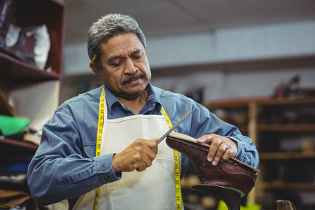 Shoemaker repairing a shoe in workshopの写真素材