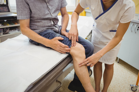 Female doctor examining patients knee at the hospitalの写真素材